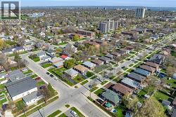 Aerial perspective of a residential neighborhood featuring detached homes with mature trees and manicured lawns - 