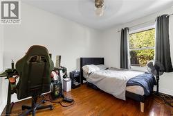 Hardwood-finish flooring featuring a window with exterior views, a ceiling fan, and white painted walls - 