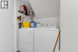 Dedicated laundry area featuring white appliances, upper wire shelving, and a sloped ceiling - 