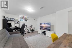 Versatile living space featuring light wood-finish flooring, a neutral color palette, a window with exterior visibility, and a built-in shelf unit - 