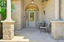 Arched entryway featuring a glass-paneled door with sidelights, stone veneer facade, and substantial stone-clad columns - 5 Coastal Court, Port Dover, ON 