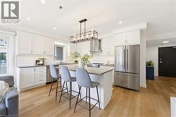 Bright kitchen featuring white cabinetry, stainless steel appliances, a center island with bar seating, a subway tile backsplash, and light wood-finish flooring - 