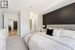 Bedroom featuring a dark accent wall, light-colored carpeting, and a white six-drawer dresser - 