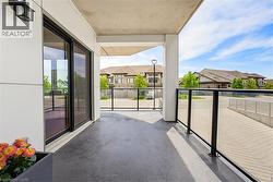 Private balcony with concrete flooring, modern glass railing, and a black exterior light fixture - 