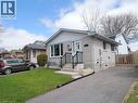 Light-colored brick exterior featuring white siding accents, a front entry with black railings, a paved driveway, and a fenced side yard - 771 Monsarrat Avenue, London, ON 