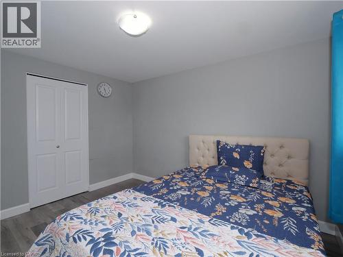Interior room featuring light gray walls, wood-finish flooring, a flush-mount ceiling light, and white bi-fold closet doors - 771 Monsarrat Avenue, London, ON 