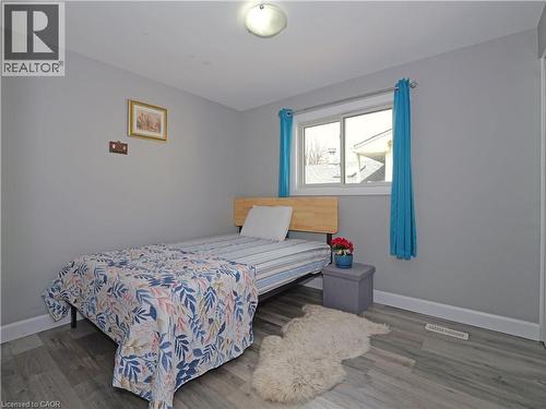 Room featuring wood-finish flooring, a double-pane window, light gray wall paint, white baseboards, and an overhead flush-mount light fixture - 771 Monsarrat Avenue, London, ON 