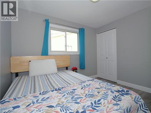 Bedroom featuring light gray walls, wood-finish flooring, a double-panel closet door, and a window with a curtain rod - 771 Monsarrat Avenue, London, ON 