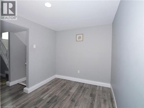 Spacious room featuring wood-finish flooring, light gray wall paint, white baseboards, and recessed ceiling lighting - 771 Monsarrat Avenue, London, ON 