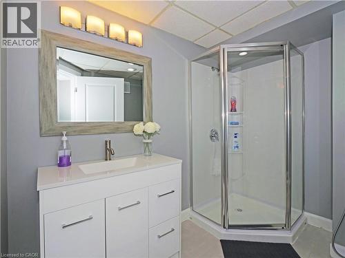 Modern bathroom featuring a white vanity with integrated sink, brushed nickel faucet, and a large framed mirror - 771 Monsarrat Avenue, London, ON 