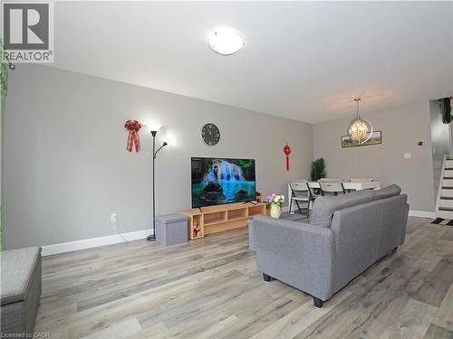 Open-concept living area featuring light gray walls, wood-finish flooring, and a contemporary chandelier in the dining space - 771 Monsarrat Avenue, London, ON 
