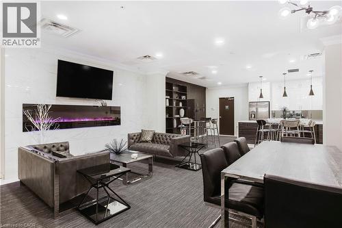 Open-concept common area featuring a contemporary electric fireplace with a wall-mounted display, marble-look accent wall, and recessed lighting - 112 King Street E Unit# Ph6, Hamilton, ON - Indoor Photo Showing Living Room