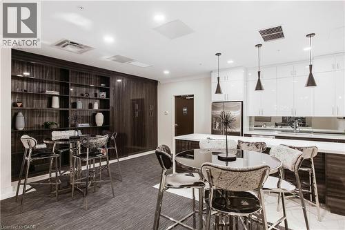 Contemporary kitchen and lounge area featuring dark wood-finish built-in shelving, white high-gloss cabinetry, a stainless steel refrigerator, and pendant lighting fixtures - 112 King Street E Unit# Ph6, Hamilton, ON - Indoor Photo Showing Dining Room