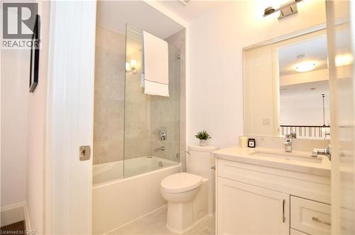 Full bathroom featuring a white vanity with integrated sink, a built-in tub with a clear glass enclosure, and a tile shower surround - 112 King Street E Unit# Ph6, Hamilton, ON - Indoor Photo Showing Bathroom
