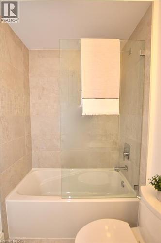 Bathtub with a partial glass shower screen, chrome fixtures, and neutral tile surround extending to the ceiling - 112 King Street E Unit# Ph6, Hamilton, ON - Indoor Photo Showing Bathroom