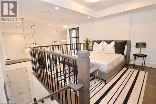 Open-concept loft space featuring a dark wood-finish flooring and a contemporary black metal and wood-tone railing system - 112 King Street E Unit# Ph6, Hamilton, ON - Indoor Photo Showing Other Room