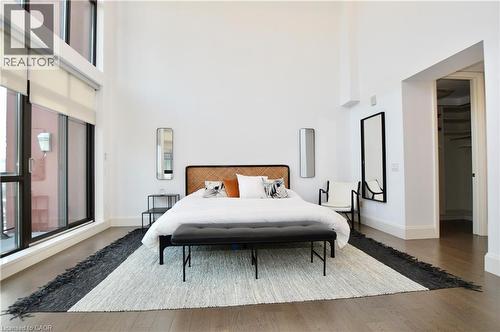Expansive room featuring high ceilings, wood-finish flooring, and large windows with integrated shades - 112 King Street E Unit# Ph6, Hamilton, ON - Indoor Photo Showing Bedroom