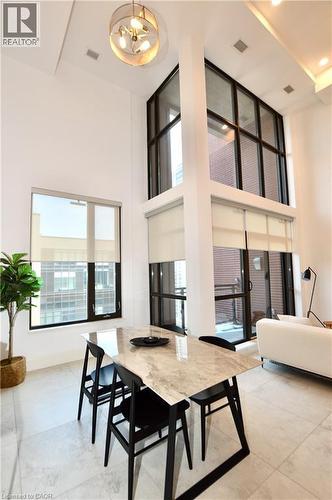 Dramatic two-story living area featuring a full wall of floor-to-ceiling windows with roller shades, recessed lighting, and a contemporary chandelier - 112 King Street E Unit# Ph6, Hamilton, ON - Indoor Photo Showing Other Room