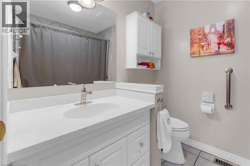 Bathroom featuring a white vanity with an integrated sink, brushed nickel faucet, wall-mounted mirror, white wall cabinetry, and tile flooring - 50 Spadara Drive, Hamilton, ON 