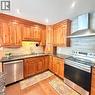 Full kitchen featuring wood cabinetry, dark countertops, subway tile backsplash, stainless steel appliances, and recessed lighting - 82 Blackwood Crescent, Hamilton, ON 