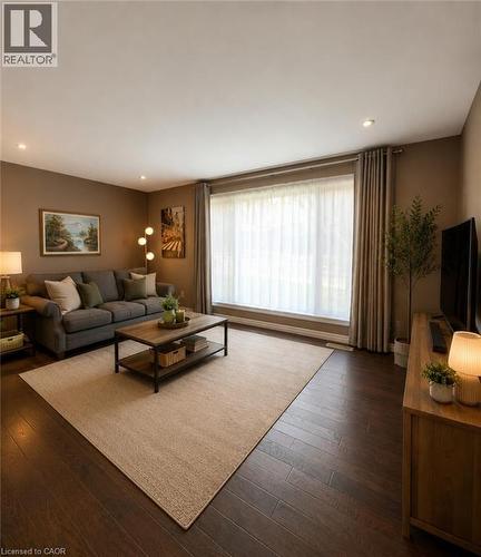 Spacious living area featuring dark wood-finish flooring, a large picture window with drapes, recessed lighting, and warm neutral wall colors - 82 Blackwood Crescent, Hamilton, ON 