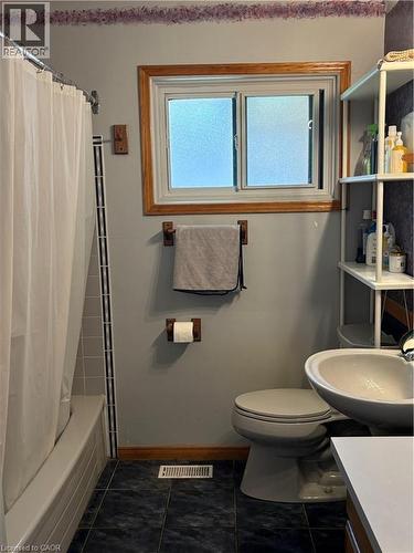 Bathroom featuring a white bathtub with tiled surround, a toilet, and a sink with a white counter - 82 Blackwood Crescent, Hamilton, ON 