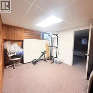 Carpeted room featuring a drop ceiling with recessed lighting, wood-paneled walls, and built-in cabinetry - 
