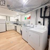 Full-size washer and dryer appliances, light wood-finish flooring, white cabinetry, recessed lighting, and a utility sink - 