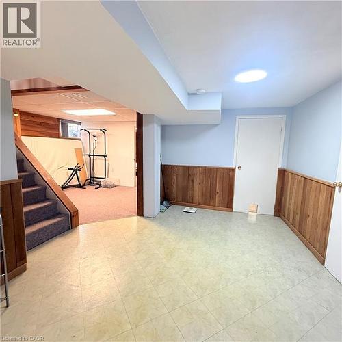 Finished lower level featuring a light blue wall color with wood paneling - 82 Blackwood Crescent, Hamilton, ON 