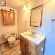 Bathroom featuring a wood vanity with integrated sink, a matching wood-framed mirror, and a wood wall cabinet - 