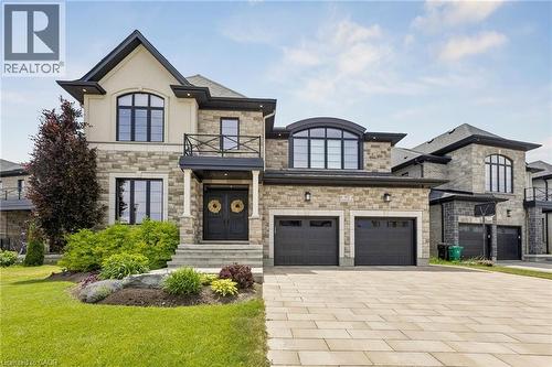 Statley and modern home with contemporary stone and stucco exterior featuring multiple gables, an oversized two-car garage with black doors, and a paver driveway - 95 Pondcliffe Drive, Kitchener, ON 