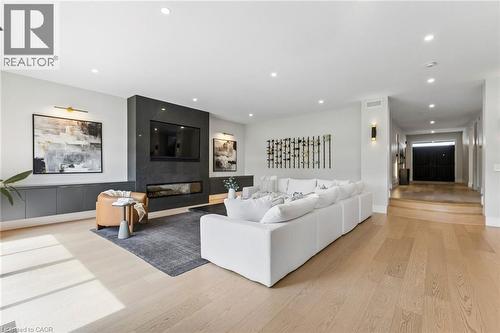 Spacious living area featuring light wood-finish flooring, recessed lighting, and a dark stone-clad fireplace with an integrated linear firebox - 95 Pondcliffe Drive, Kitchener, ON 
