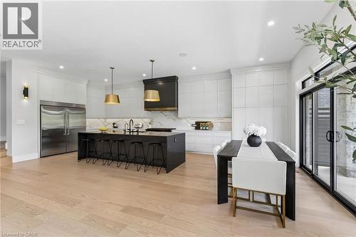 Designer kitchen featuring modern and sleek custom cabinetry, 10' central island clad in quart countertop with waterfall edge, high-end stainless steel refridgerator, 6 burner Dacor stove, integrated - 95 Pondcliffe Drive, Kitchener, ON 