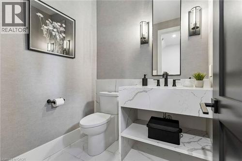 Powder room featuring a floating vanity with a waterfall edge countertop, undermount sink, and matte black fixtures - 95 Pondcliffe Drive, Kitchener, ON 