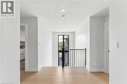 Upper-level hallway featuring oak flooring, recessed lighting, contemporary black metal and wood handrail - 95 Pondcliffe Drive, Kitchener, ON 