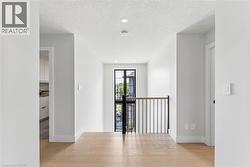 Upper-level hallway featuring oak flooring, recessed lighting, contemporary black metal and wood handrail - 