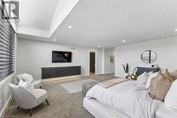 Spacious room featuring vaulted ceilings with recessed lighting, plush carpeting, and light-filtering window treatments - 