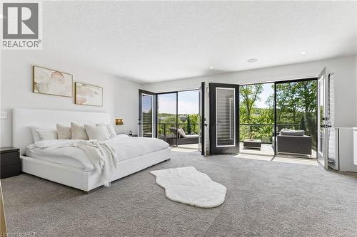 Room featuring light gray carpeting, recessed ceiling lighting, and expansive glass doors opening to an outdoor balcony - 95 Pondcliffe Drive, Kitchener, ON 