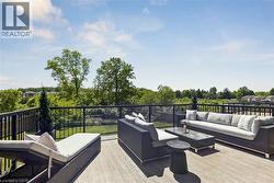 Expansive rooftop terrace featuring wood-finish decking, black metal railings, and clear glass panels - 