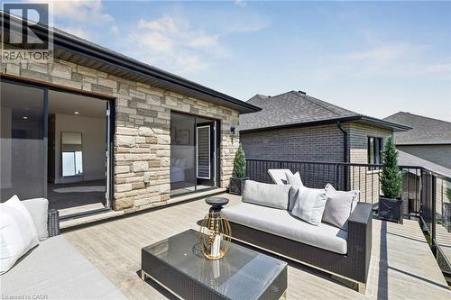 Expansive outdoor deck featuring wood-finish flooring, a stone facade, and a black metal railing - 95 Pondcliffe Drive, Kitchener, ON 