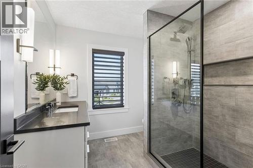 Spa-inspired ensuite bathroom featuring a glass-enclosed shower with tile surround, niche, lighting scones, and quartz countertop floating vanity with undermount lighting - 95 Pondcliffe Drive, Kitchener, ON 