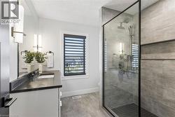 Spa-inspired ensuite bathroom featuring a glass-enclosed shower with tile surround, niche, lighting scones, and quartz countertop floating vanity with undermount lighting - 