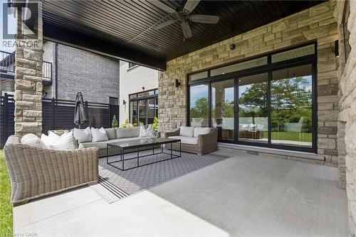 Expansive covered patio featuring stone columns, a stone-clad exterior, and a built-in SUNBRITE TV and gas fireplace. - 95 Pondcliffe Drive, Kitchener, ON 