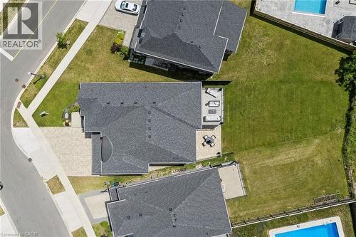 Overhead shot of the expansive property featuring a large backyard with manicured lawn, paver patio, and paved driveway, backing onto protected greenspace and natural area, with spring-fed natural pon - 95 Pondcliffe Drive, Kitchener, ON 