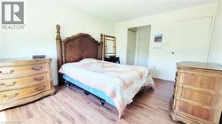 Bedroom featuring wood-finish flooring, light-toned walls, and a white interior door - 