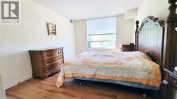Room featuring wood-finish flooring, a window with roller shades, and light-toned walls - 