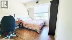 Spacious room featuring wood-finish flooring, a large window with roller shades, and light-colored walls - 