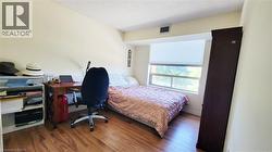 Room featuring wood-finish flooring, a large window with a roller blind, and light-toned walls - 