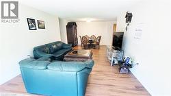 Open-concept living area with wood-finish flooring, white walls, and recessed lighting - 