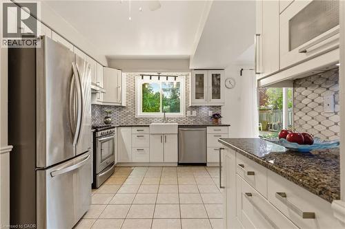 Kitchen featuring stainless steel appliances, white cabinetry, tile backsplash, and a farmhouse sink - 17 Piper Place, Caledonia, ON 